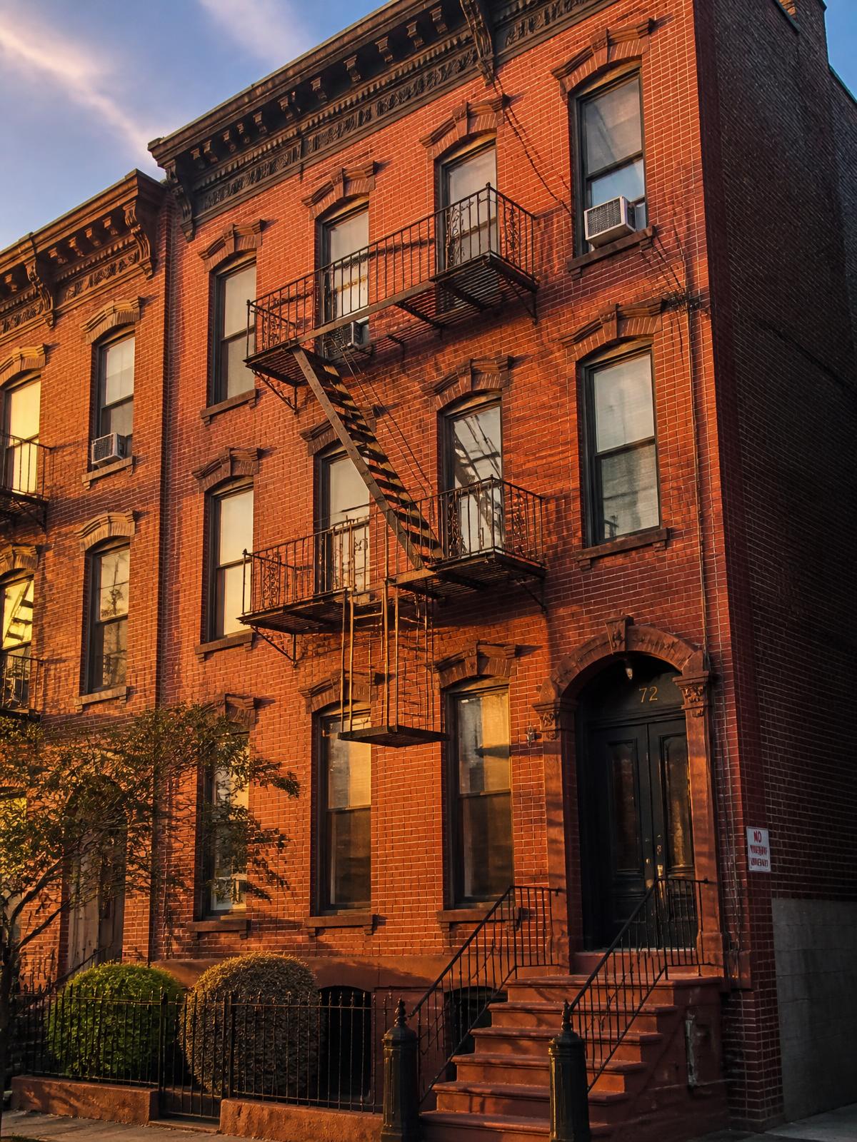 Red brick Newark residential building with black fire escapes at golden hour